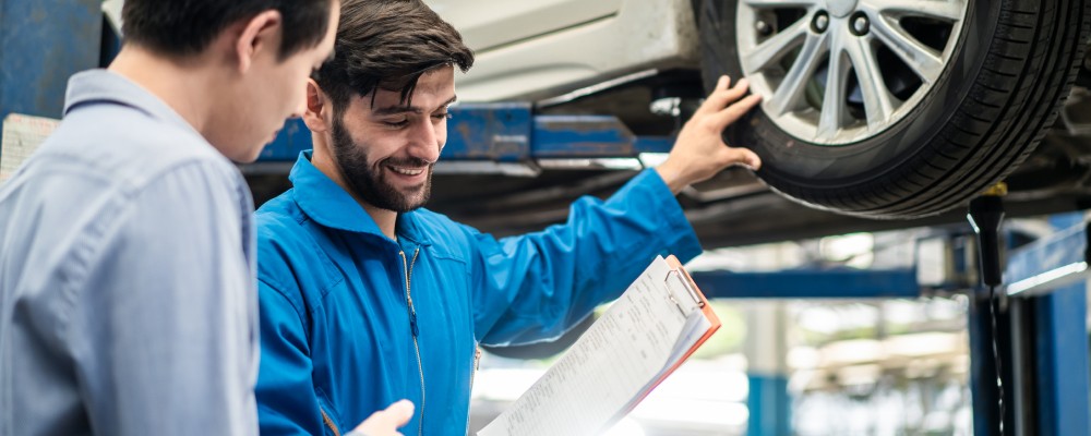 The mechanic is showing the cost of wheel alignment maintenance to the car owner, (speedalternators.com)