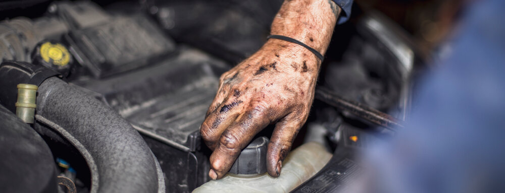 dirty hand opening coolant plug of car engine, (speedalternators.com).